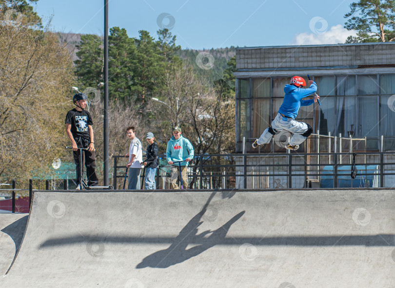 Скачать Россия, Красноярск 02 мая 2025г. Подросток на трюковом самокате в скейт-парке выполняет трюк во время прыжка. фотосток Ozero
