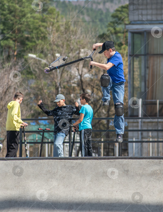 Скачать Россия, Красноярск 02 мая 2025г. Подросток на трюковом самокате в скейт-парке выполняет трюк во время прыжка. фотосток Ozero