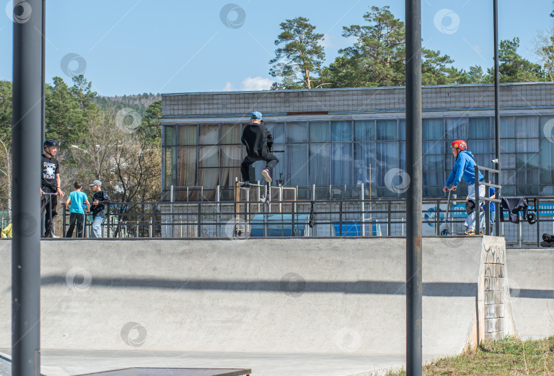 Скачать Россия, Красноярск 02 мая 2025г. Подросток на трюковом самокате в скейт-парке выполняет трюк во время прыжка. фотосток Ozero