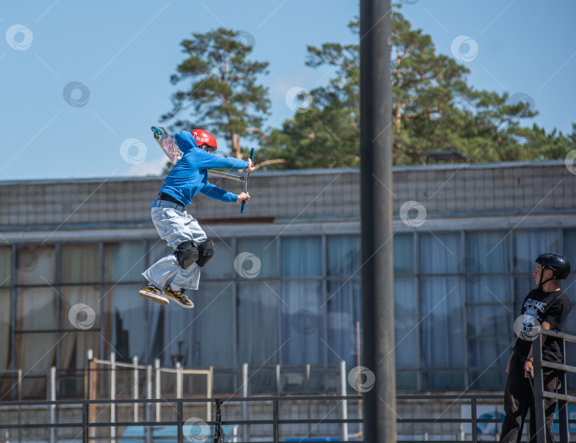Скачать Россия, Красноярск 02 мая 2025г. Подросток на трюковом самокате в скейт-парке выполняет трюк во время прыжка. фотосток Ozero