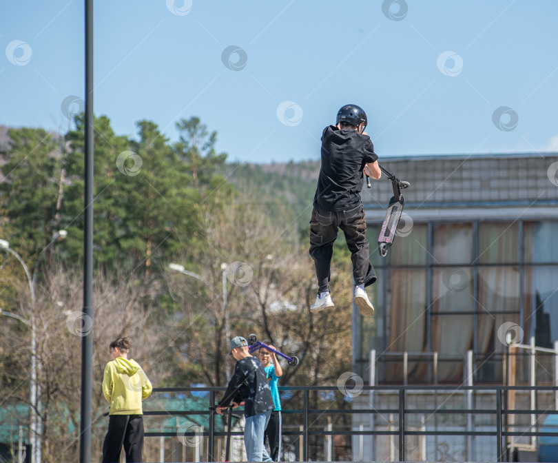 Скачать Россия, Красноярск 02 мая 2025г. Подросток на трюковом самокате в скейт-парке выполняет трюк во время прыжка. фотосток Ozero