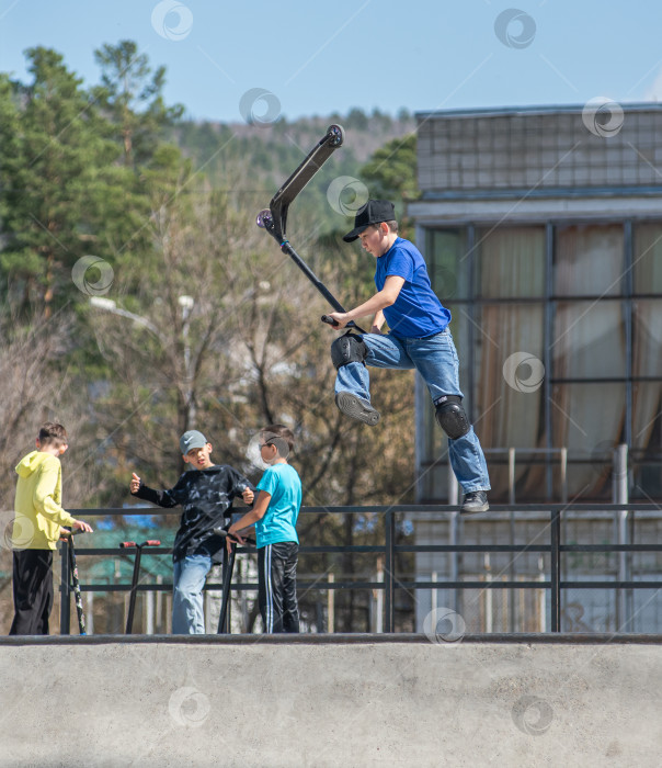 Скачать Россия, Красноярск 02 мая 2025г. Подросток на трюковом самокате в скейт-парке выполняет трюк во время прыжка. фотосток Ozero