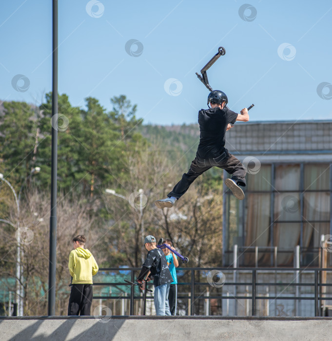 Скачать Россия, Красноярск 02 мая 2025г. Подросток на трюковом самокате в скейт-парке выполняет трюк во время прыжка. фотосток Ozero