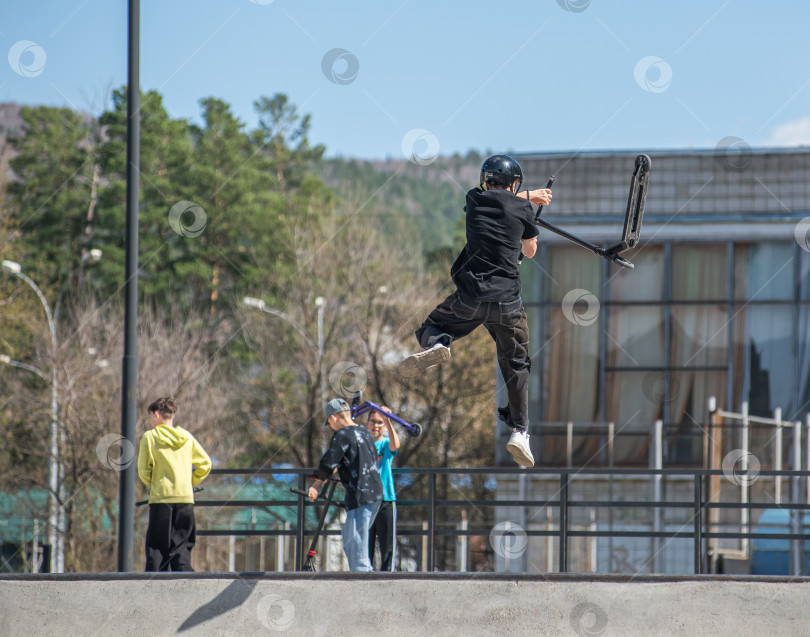 Скачать Россия, Красноярск 02 мая 2025г. Подросток на трюковом самокате в скейт-парке выполняет трюк во время прыжка. фотосток Ozero