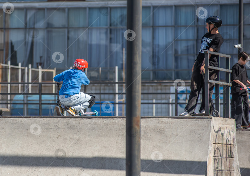 Скачать Россия, Красноярск 02 мая 2025г. Подросток на трюковом самокате в скейт-парке выполняет трюк во время прыжка. фотосток Ozero