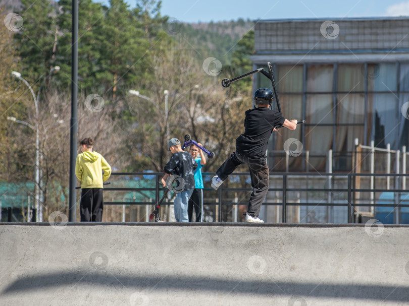 Скачать Россия, Красноярск 02 мая 2025г. Подросток на трюковом самокате в скейт-парке выполняет трюк во время прыжка. фотосток Ozero
