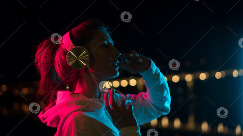 Скачать Тысячелетняя Девушка Слушает музыку Неоновый свет на открытом воздухе фотосток Ozero