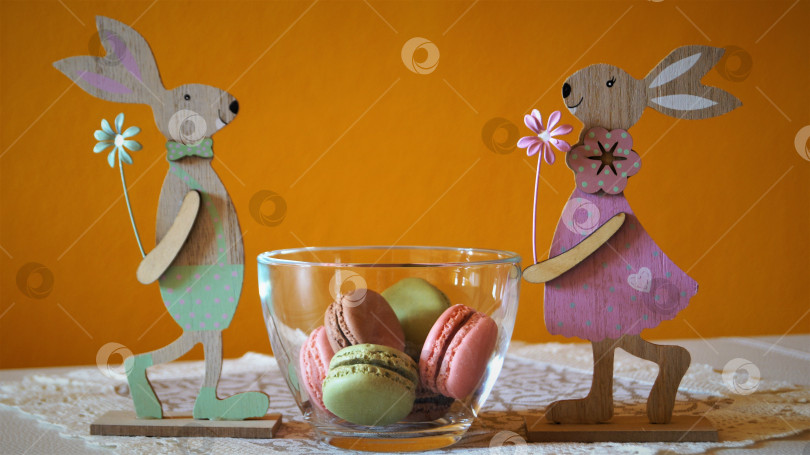 Скачать разноцветные макаронс в стеклянной вазе с деревянными зайцами фотосток Ozero