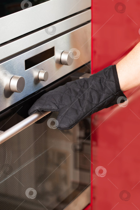 Скачать мужчина в черном поварском фартуке на кухне, на руках варежки фотосток Ozero