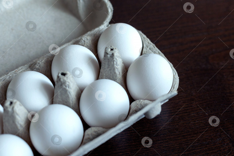 Скачать Упаковка из дюжины органических яиц свободного выгула от разных кур разных цветов и размеров, выделенных на темном фоне. фотосток Ozero