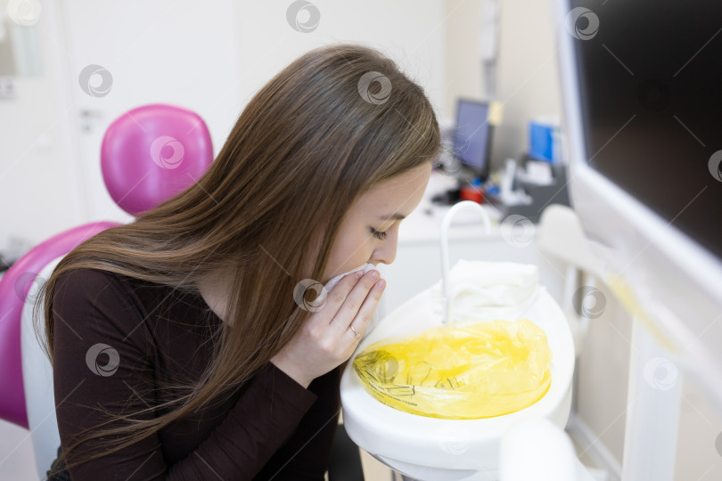 Скачать Пациент вытирает рот салфеткой после посещения стоматолога фотосток Ozero