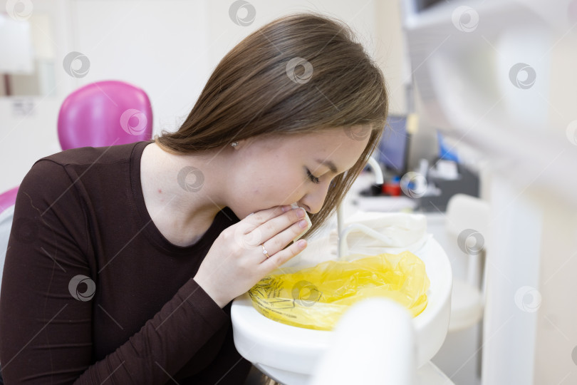 Скачать Пациент вытирает рот салфеткой после посещения стоматолога фотосток Ozero