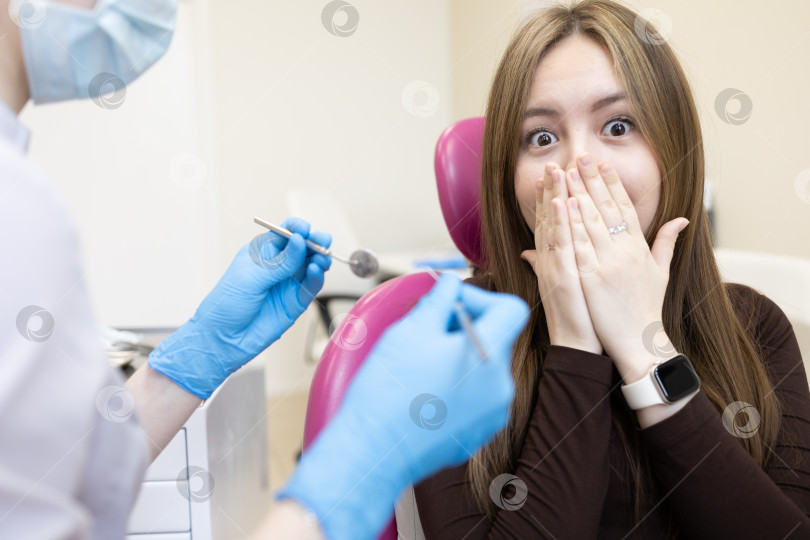 Скачать Пациентка боится стоматолога и закрывает рот руками. женщина, сидящая в стоматологическом кресле фотосток Ozero