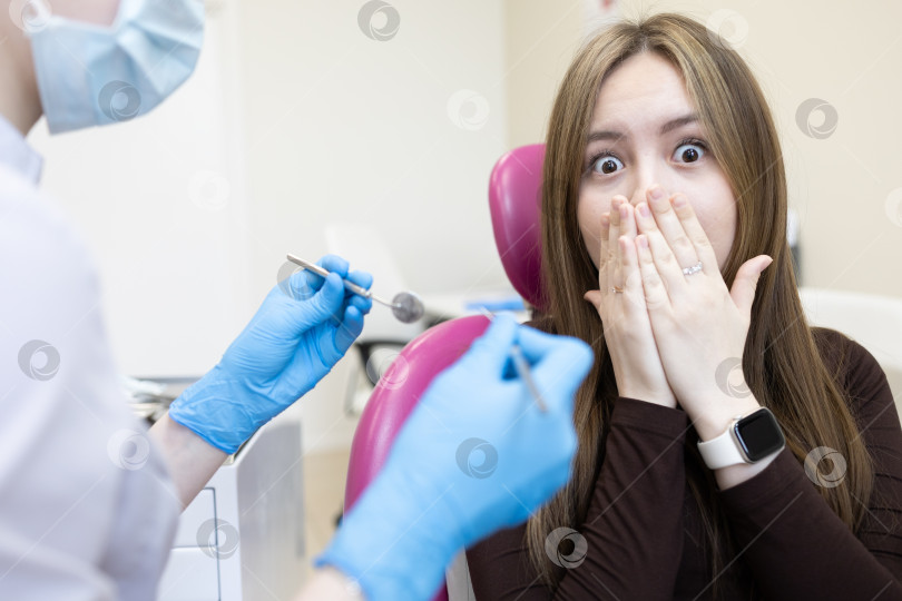 Скачать Пациентка боится стоматолога и закрывает рот руками. женщина, сидящая в стоматологическом кресле фотосток Ozero