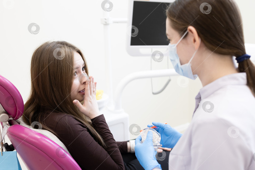 Скачать Пациентка боится стоматолога и закрывает рот руками. женщина, сидящая в стоматологическом кресле фотосток Ozero