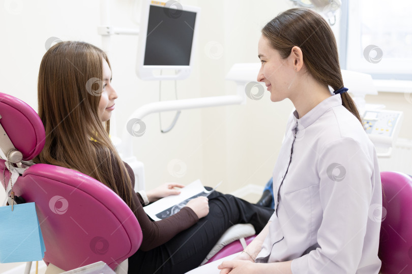 Скачать Стоматолог консультирует пациента, делая рентгеновский снимок зубов. Стоматолог показывает пациенту рентгеновский снимок фотосток Ozero
