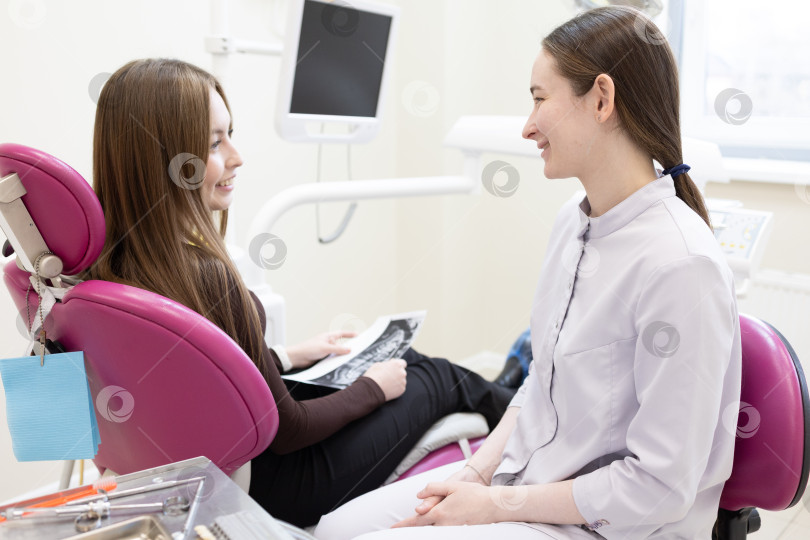 Скачать Стоматолог консультирует пациента, делая рентгеновский снимок зубов. Стоматолог показывает пациенту рентгеновский снимок фотосток Ozero