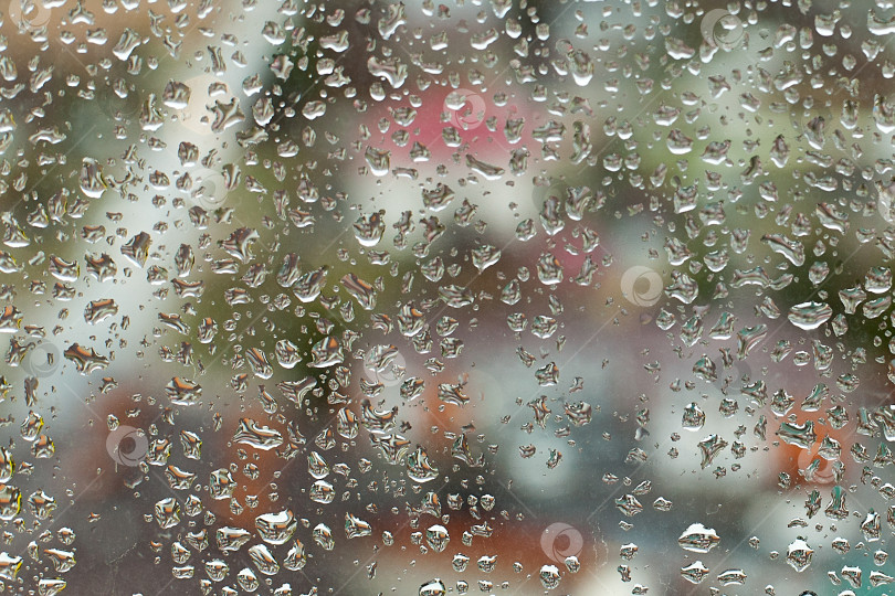 Скачать Капли дождевой воды с домами на заднем плане в городе с темными облаками. Капли дождевой воды на стекле во время дождя, темные облака и детализированные капли воды. Капли дождя на поверхности оконных стекол Естественные фотосток Ozero