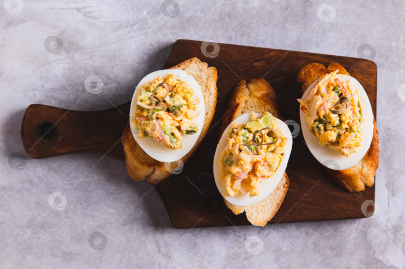 Скачать Крупный план жареных яиц с помидорами и авокадо на тостах на доске, вид сверху фотосток Ozero