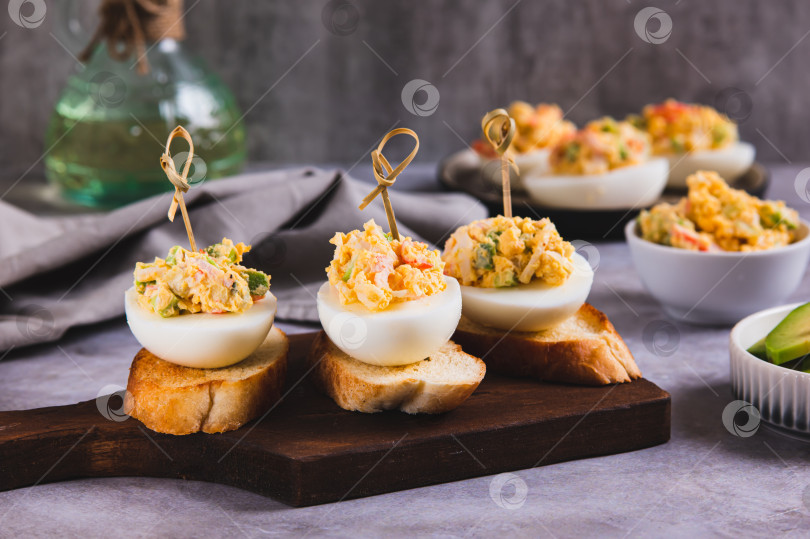 Скачать Запеченные яйца с помидорами и авокадо на тостах на доске фотосток Ozero