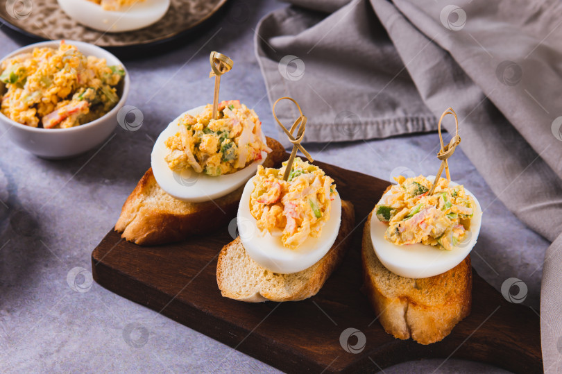 Скачать Канапе с жареными яйцами на тостах на доске на столе фотосток Ozero