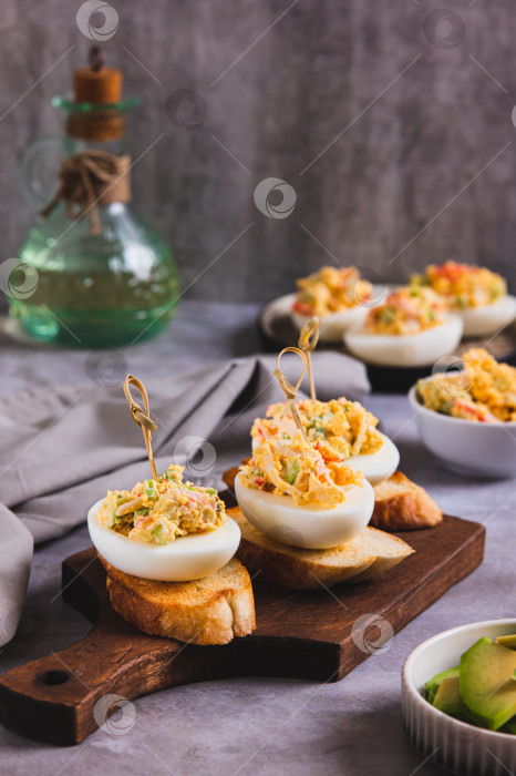 Скачать Жареные яйца с помидорами и авокадо на тостах на доске в вертикальном положении фотосток Ozero