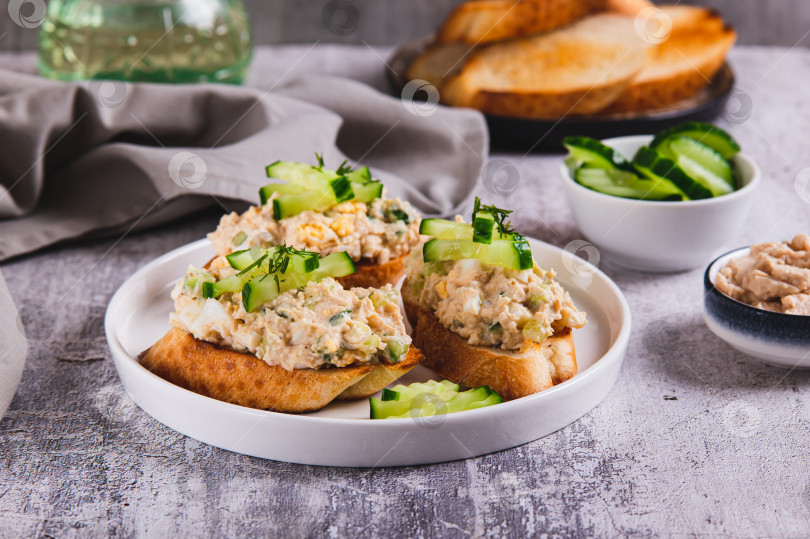 Скачать Вкусные бутерброды с салатом из печени трески, яйцом и огурцом на тарелке на столе фотосток Ozero