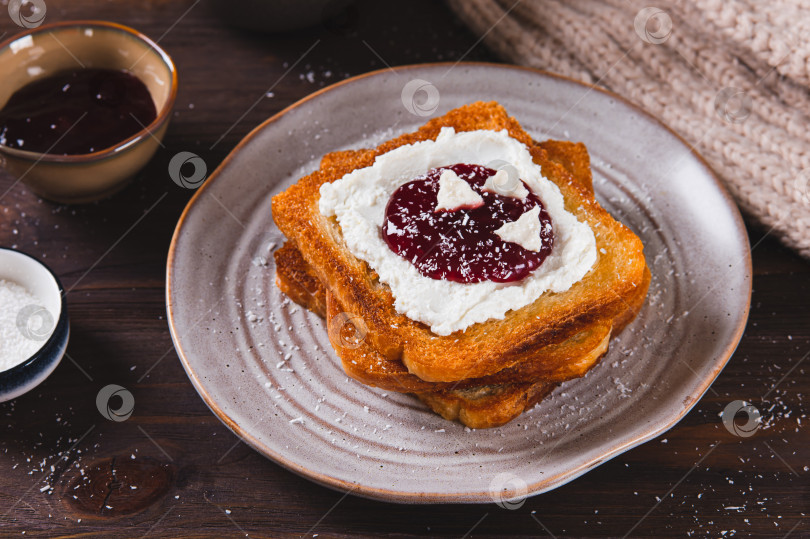 Скачать Вкусные тосты со сливочным сыром, джемом, пастилой и кокосовой стружкой на тарелке на столе фотосток Ozero