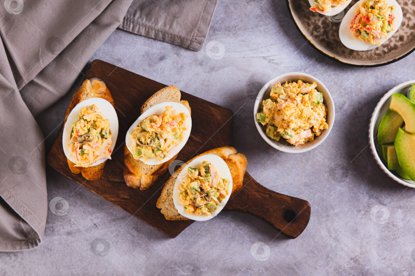 Скачать Запеченные яйца с помидорами и авокадо на тостах на доске, вид сверху фотосток Ozero
