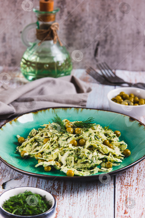 Скачать Зеленый салат с капустой, горошком и укропом на тарелке на столе в вертикальном положении фотосток Ozero