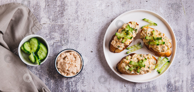 Скачать Салат из печени трески, яиц и огурцов с тостами на тарелке на столешнице посмотреть веб-баннер фотосток Ozero