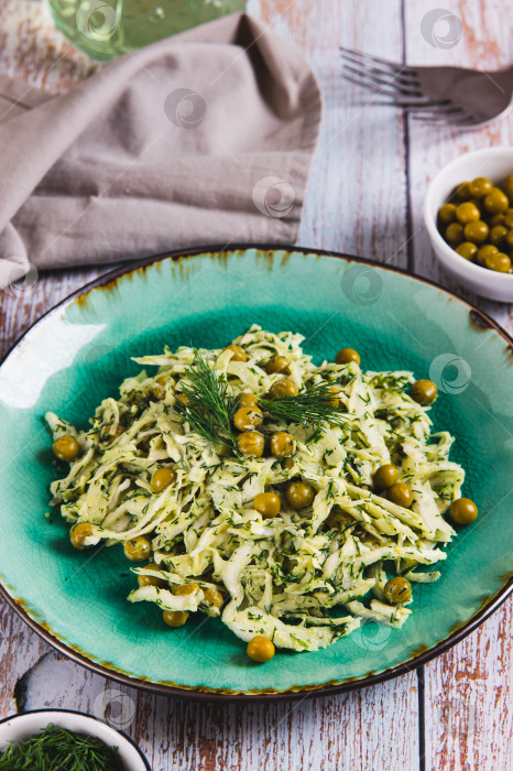 Скачать Вегетарианский салат с капустой, зеленым горошком и зеленью на тарелке на столе в вертикальном положении фотосток Ozero