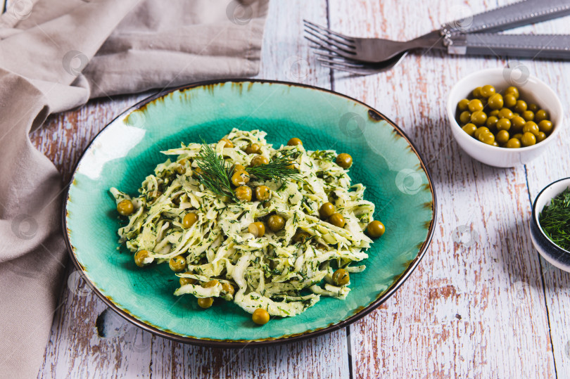 Скачать Вегетарианский салат с капустой, зеленым горошком и зеленью на тарелке на стол фотосток Ozero