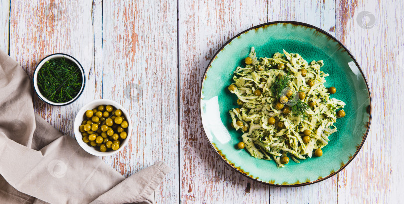 Скачать Вегетарианский салат с капустой, зеленым горошком и зеленью на тарелке на столешнице посмотреть веб-баннер фотосток Ozero