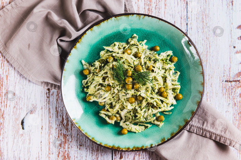 Скачать Крупный план зеленого салата с капустой, горошком и укропом на тарелке на столе, вид сверху фотосток Ozero