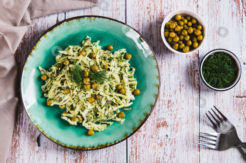 Скачать Зеленый салат с капустой, горошком и укропом на тарелке на столе вид сверху фотосток Ozero