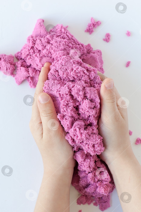 Скачать Фиолетовый кинетический песок в руке, выделенный на белом фоне. Цветной песок для лепки для детей. фотосток Ozero