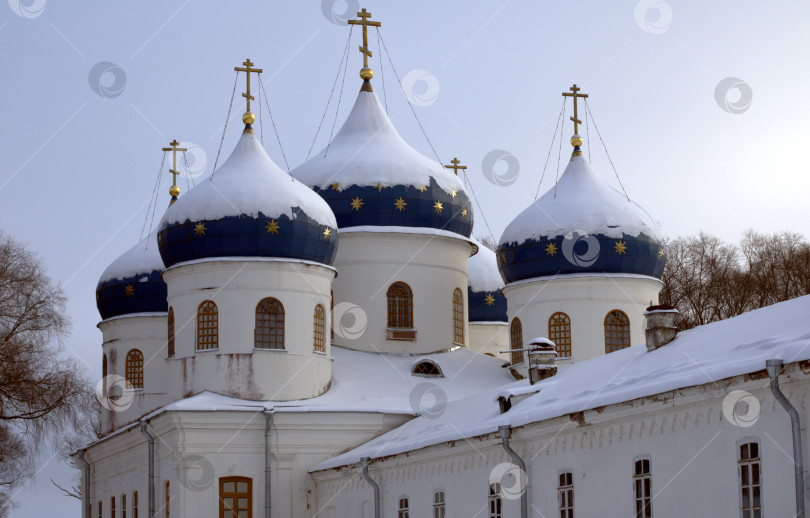 Скачать Крестовоздвиженский Собор с синими куполами в снегу в Юрьевом монастыре в Великом Новгороде. фотосток Ozero