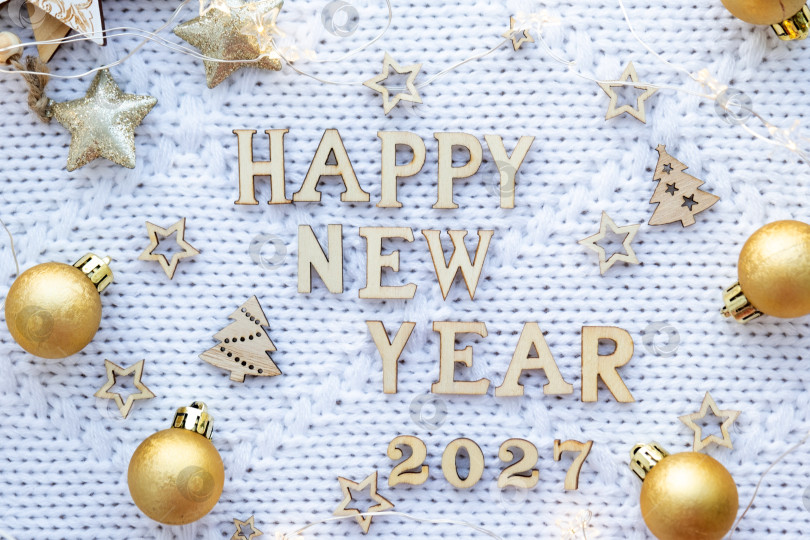 Скачать Деревянные цифры с Новым 2027 годом на уютном праздничном белом вязаном фоне с блестками, звездами, огнями гирлянд. Поздравление, открытка. Календарь, обложка фотосток Ozero