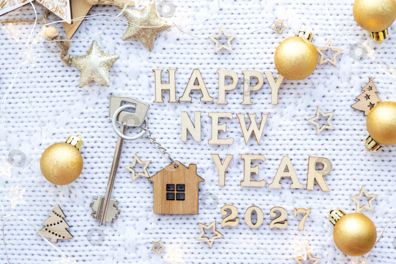 Скачать Ключ от дома с брелком-дача на праздничном фоне со звездами, огоньками гирлянд. Деревянные буквы на Новый 2027 год, поздравительная открытка. Покупка, строительство, переезд, ипотека, страхование фотосток Ozero