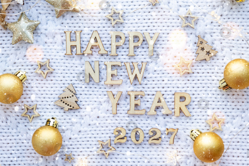 Скачать Деревянные цифры с Новым 2027 годом на уютном праздничном белом вязаном фоне с пайетками, звездами, огнями гирлянд. Поздравление, открытка. Календарь, обложка фотосток Ozero