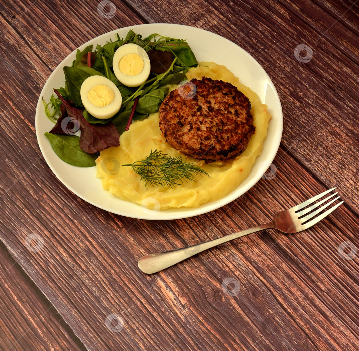 Скачать Говяжий стейк на гриле с картофельным пюре и нарезанным вкрутую яйцом на зеленых листьях и вилке. фотосток Ozero