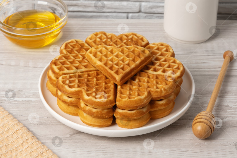 Скачать Вафли в форме сердечка подаются на тарелке с медом и сиропом рядом фотосток Ozero