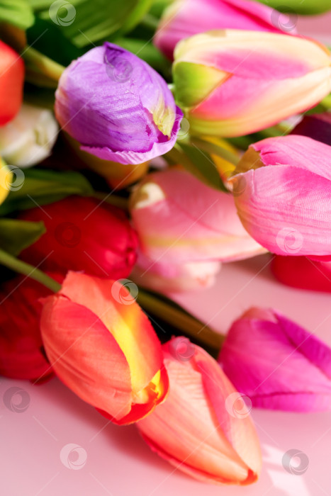Скачать Имитации свежих тюльпанов укладываются вплотную друг к другу на чистой поверхности. Цветы имеют различные оттенки, такие как розовый, красный, фиолетовый и оранжевый. Красота весны расцветает с помощью искусственных цветов, искусственных тюльпанов фотосток Ozero
