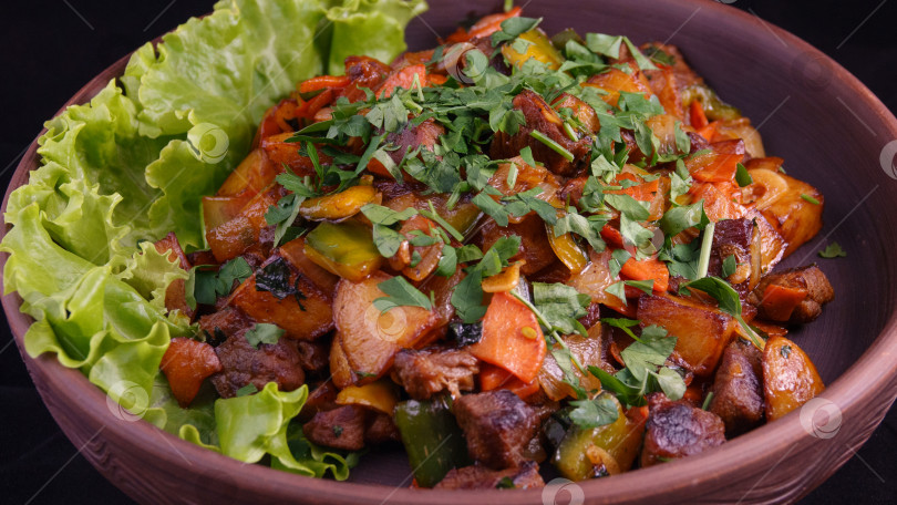 Скачать Жареный картофель с мясом на темном фоне в тарелке из глины фотосток Ozero