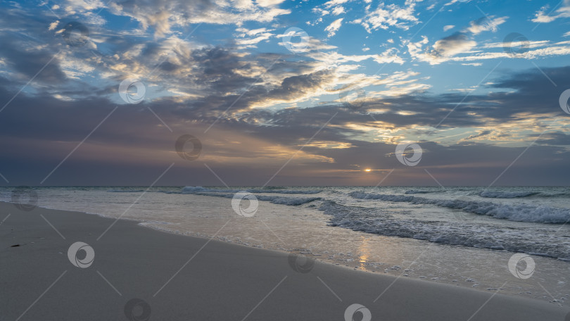 Скачать Закат над океаном. Солнце стоит низко, выглядывая из-за облаков. фотосток Ozero