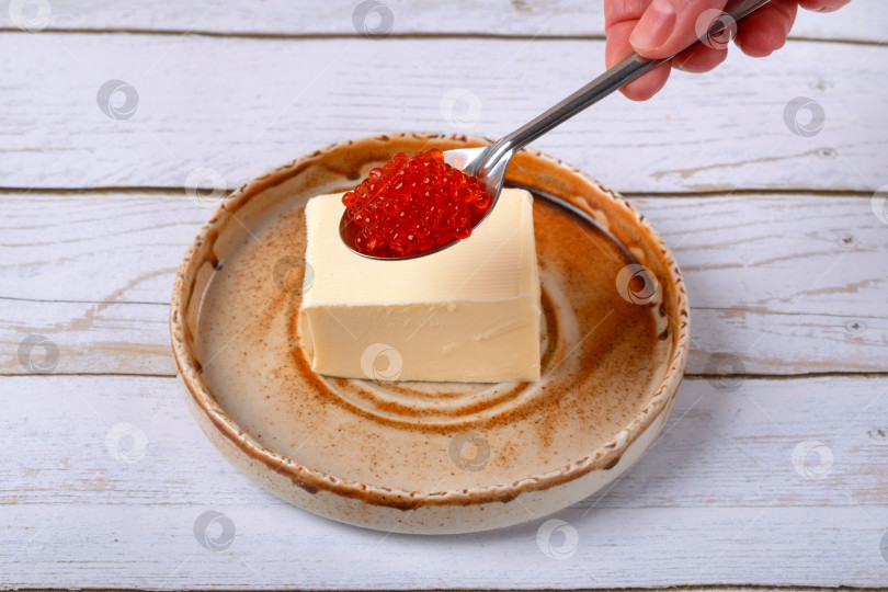 Скачать Красная икра в ложке и сливочное масло на керамической тарелке на белом столе фотосток Ozero