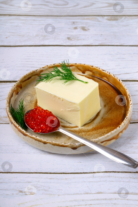 Скачать Красная икра в ложке и сливочное масло на керамической тарелке на белом столе фотосток Ozero