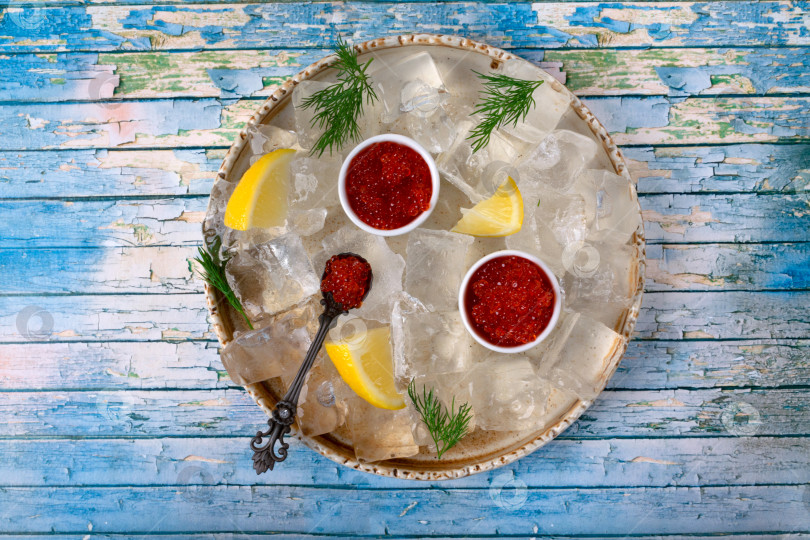 Скачать Набор из красной икры в керамических вазочках и ложках, дольки лимона и веточка укропа на подносе со льдом фотосток Ozero