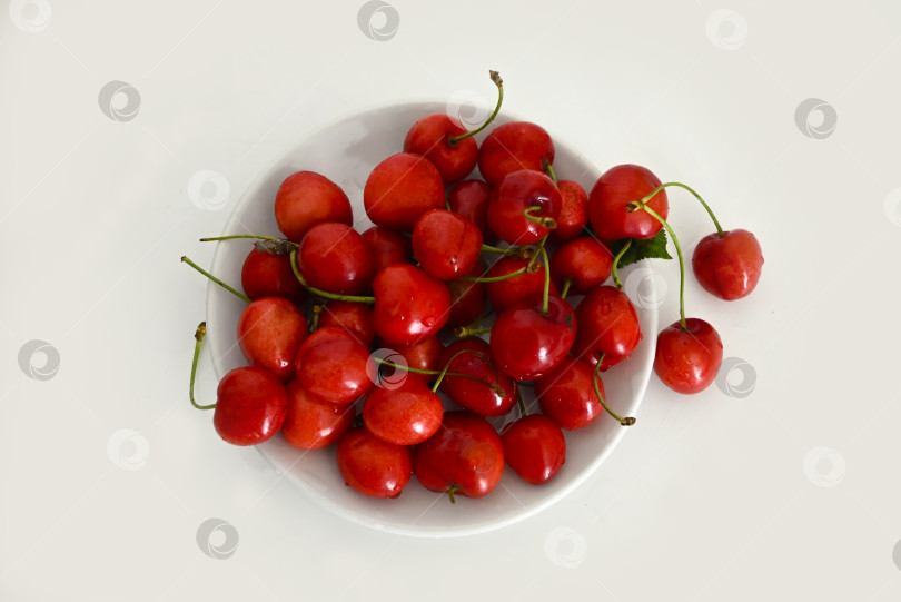 Скачать Вид сверху на тарелку со спелой черешней на светлом фоне фотосток Ozero